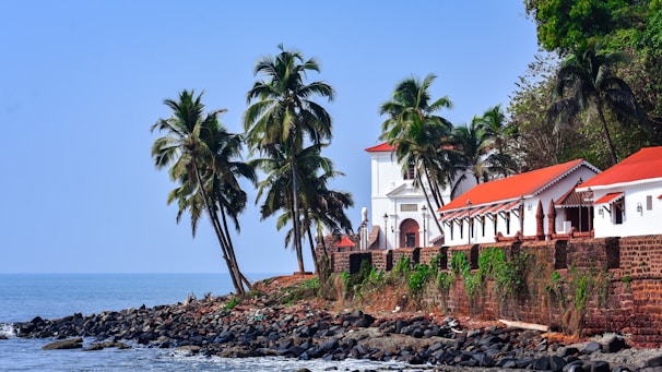 a white building with a red roof next to a body of water
