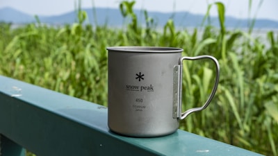 Close-up of a rugged stainless steel bottle with a mountain landscape in the background.