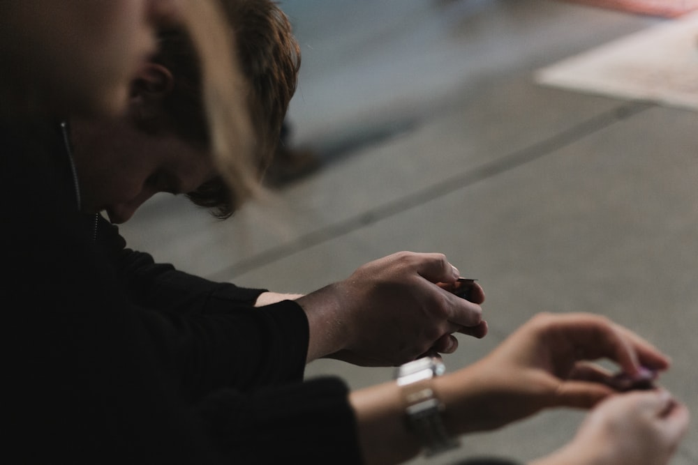 two people sitting on the floor looking at their cell phones