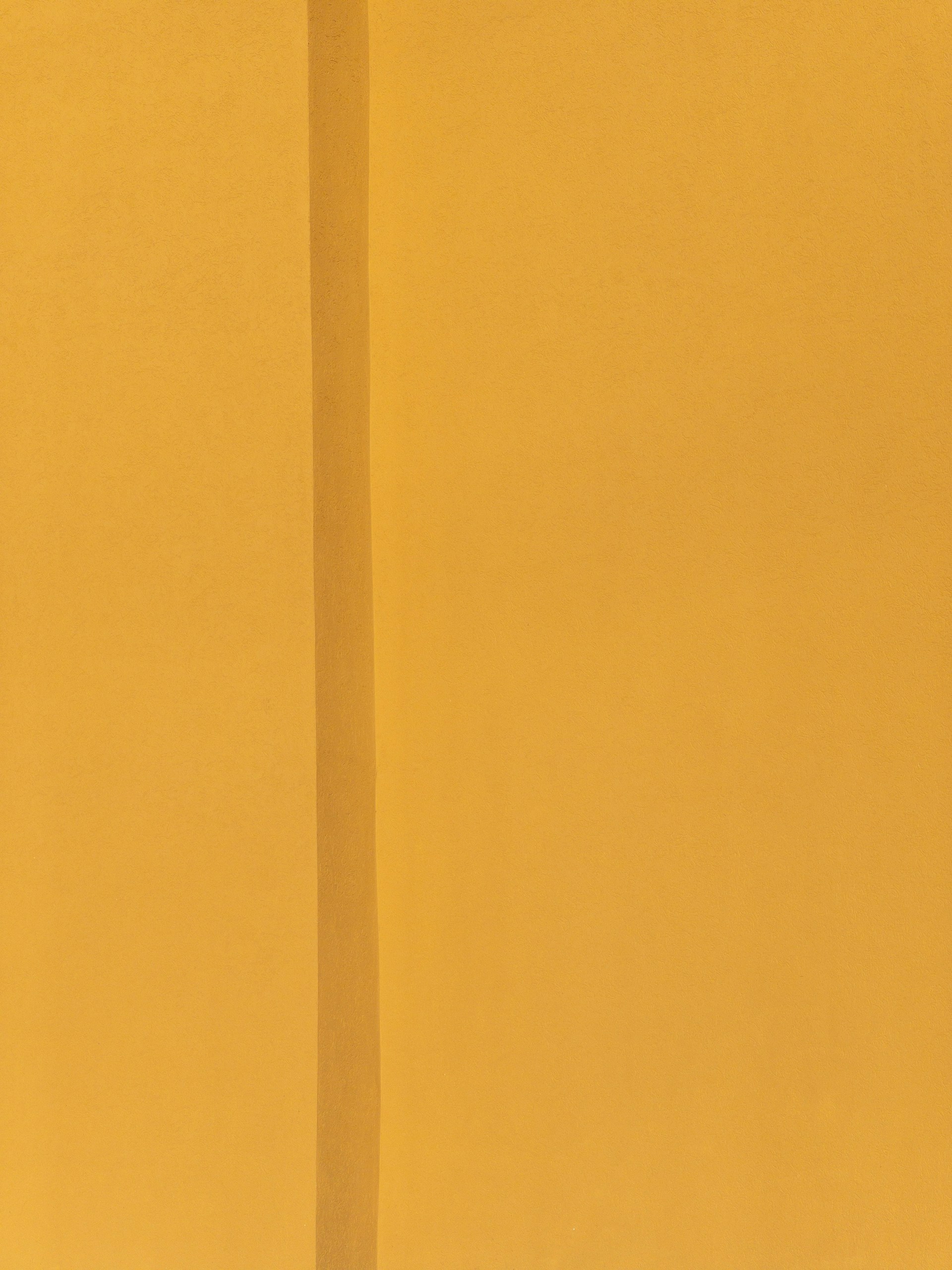 a yellow wall with a clock on the top of it