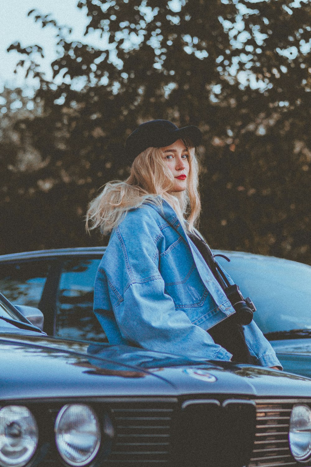 a woman leaning on the hood of a car