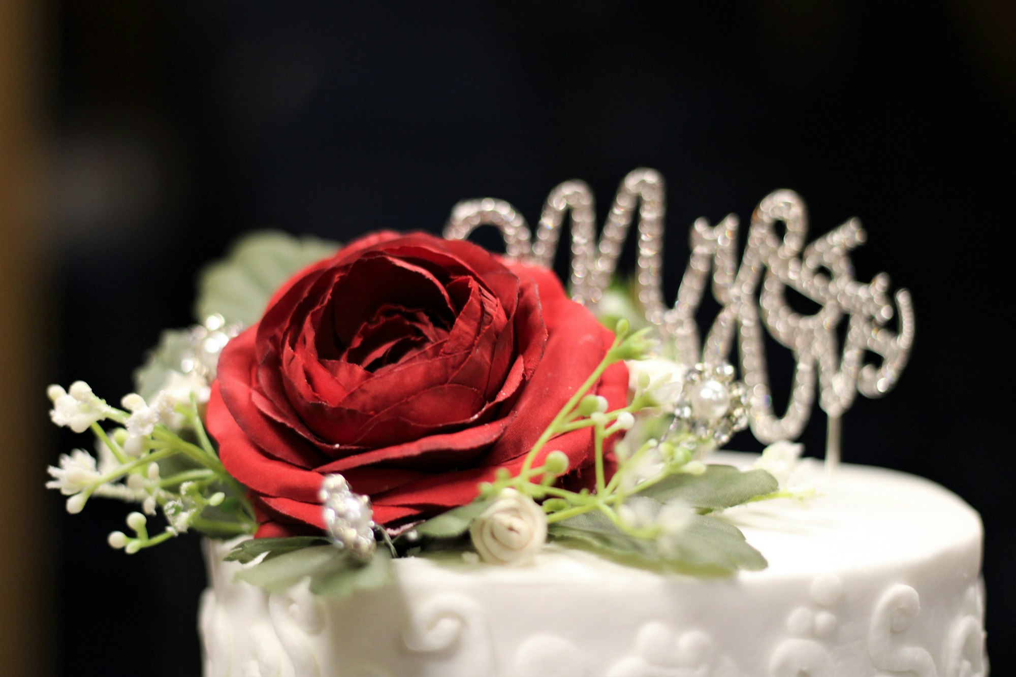 Rosa con la scritta dietro Mister e Miss sopra alla torta nuziale simbolo di un matrimonio elegante e raffinato