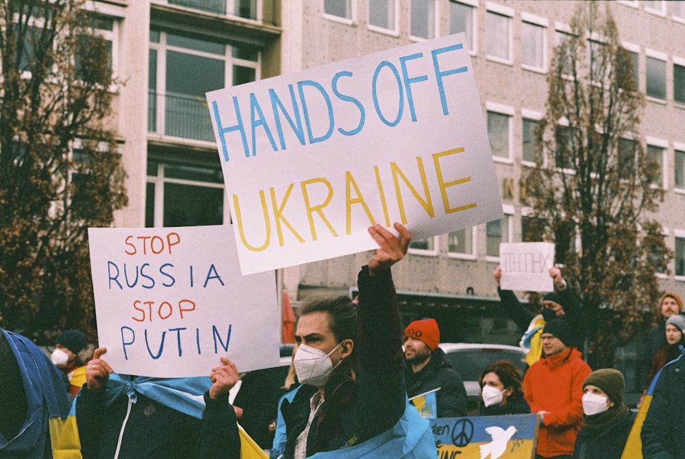 a group of people holding signs and wearing masks