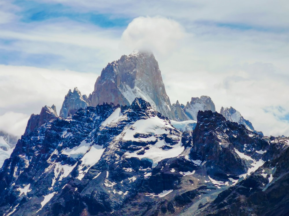 a very tall mountain covered in snow under a cloudy sky