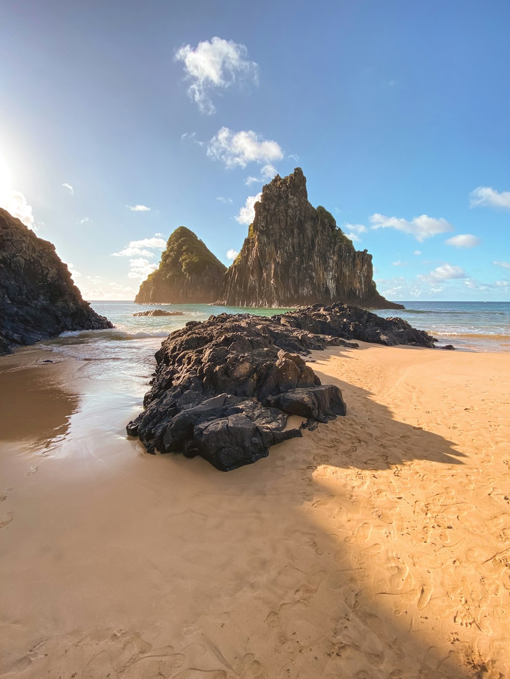 a sandy beach with a rock formation in the background