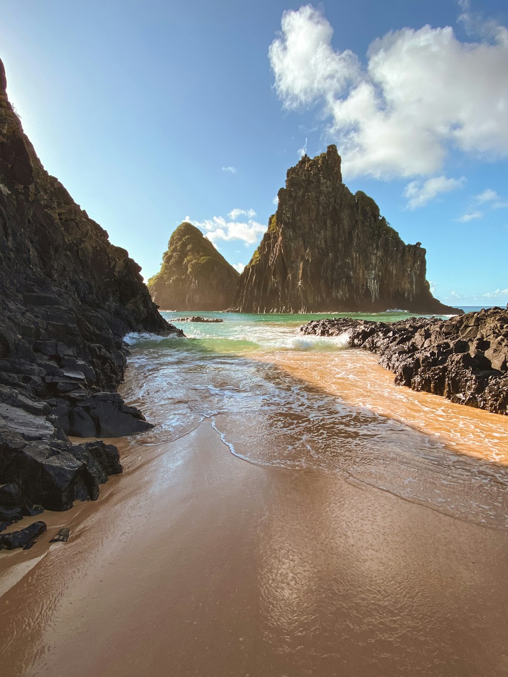 a sandy beach next to a rocky cliff