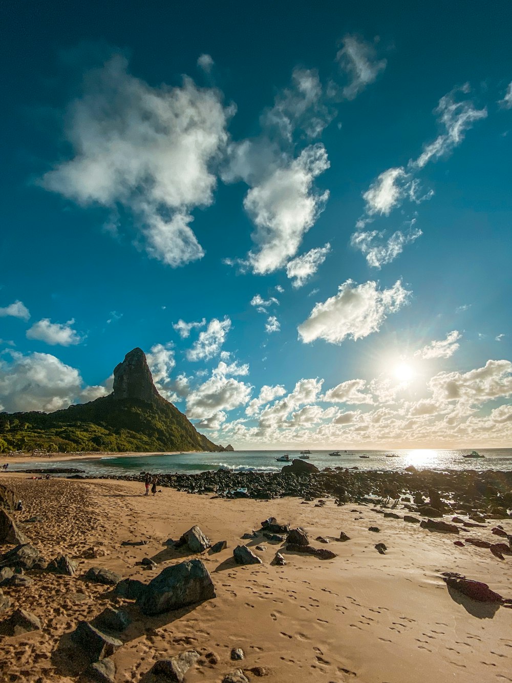 a person walking on a beach with a mountain in the background