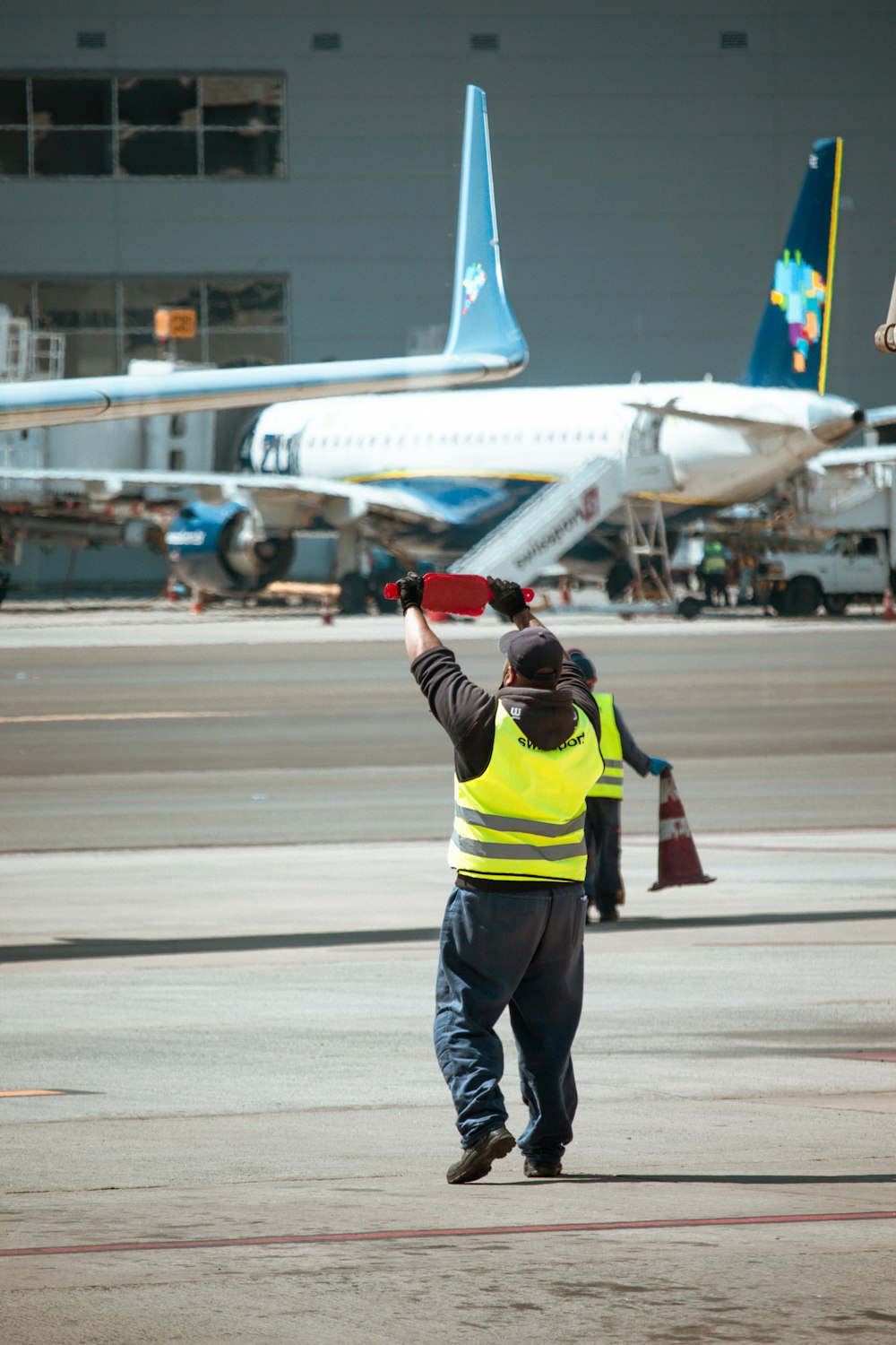 a man in a yellow vest is walking towards an airplane