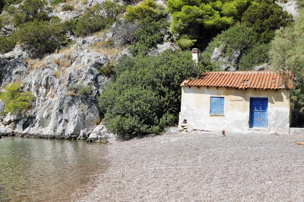 a small building with a blue door next to a body of water