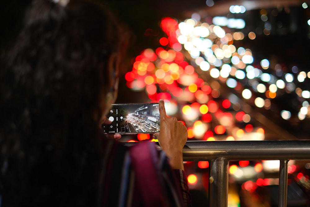 a woman taking a picture of a city at night