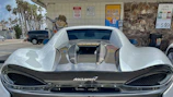 Silver McLaren 720S parked on a palm-lined Miami street at dusk.