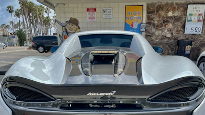 Silver McLaren 720S parked on a palm-lined Miami street at dusk.