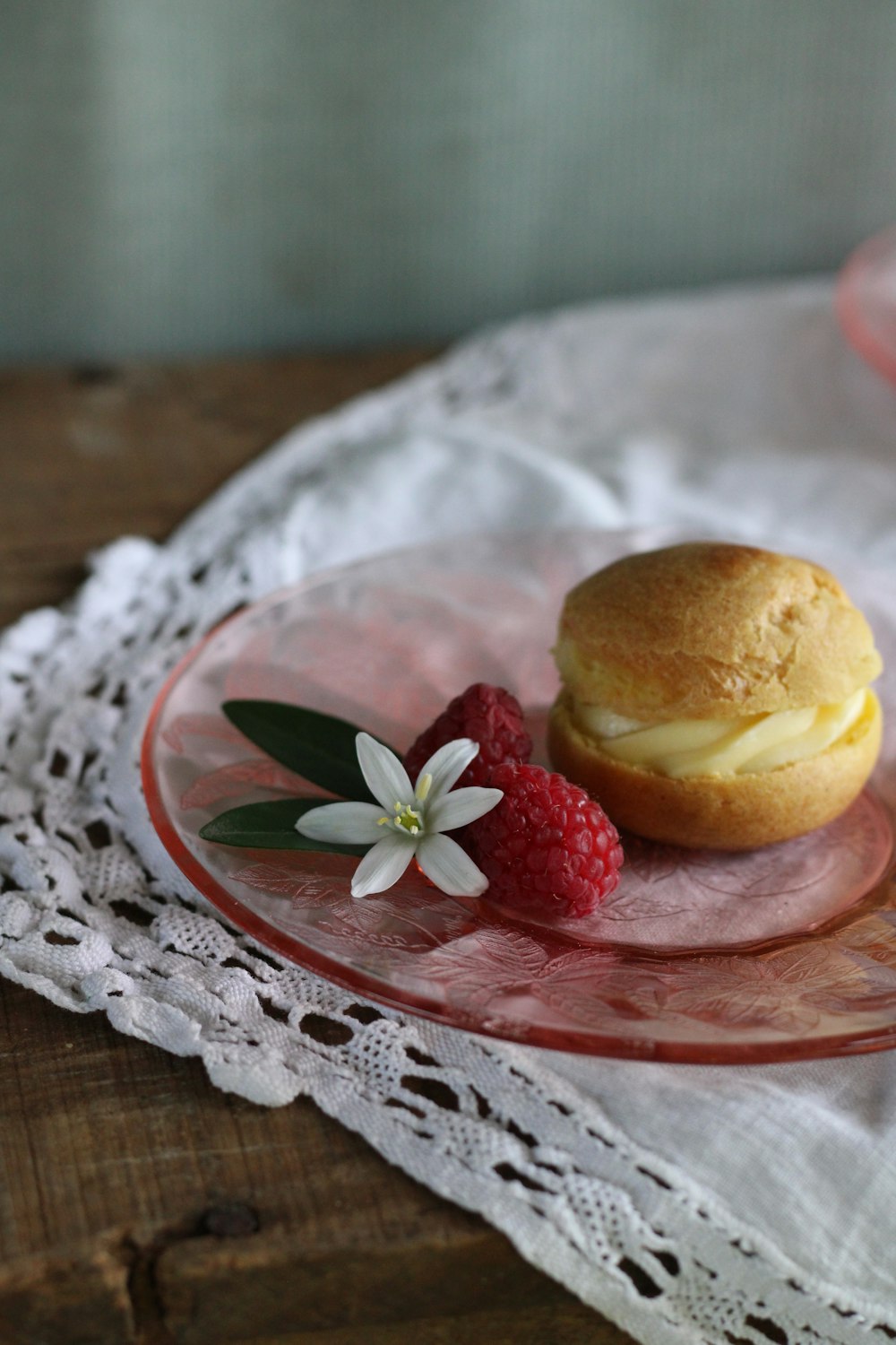 a muffin and a raspberry on a glass plate