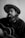 A person with long hair and a beard is wearing a wide-brimmed hat while holding an acoustic guitar. They have a cigarette in their mouth, and smoke is gently rising. The person wears a dark shirt, and the image is in black and white, giving it a classic, timeless feel.