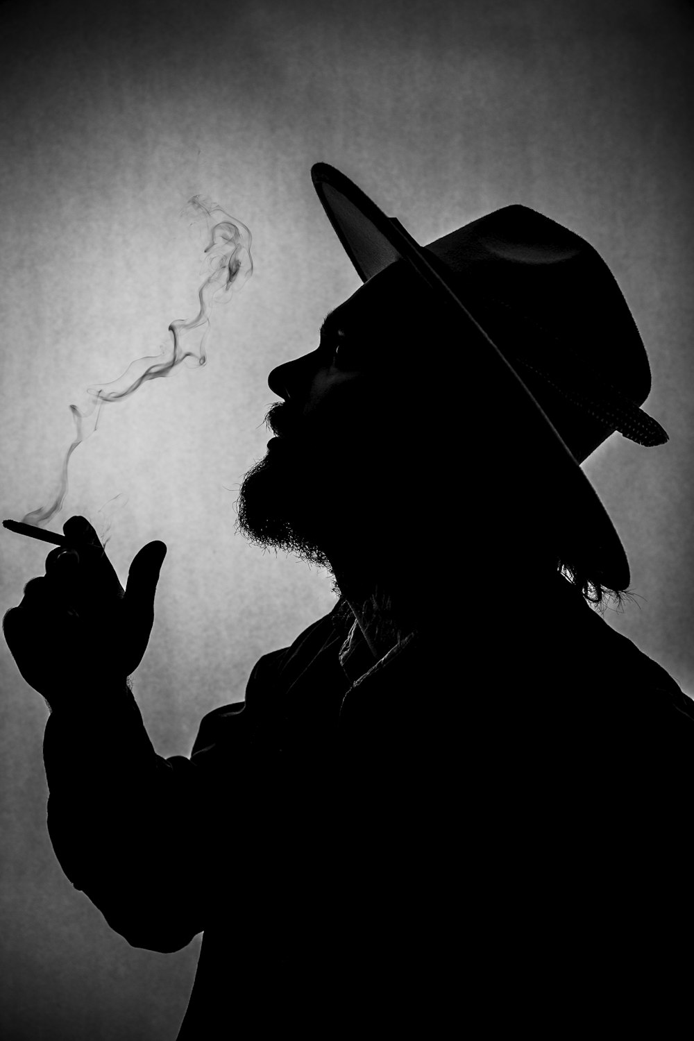 Un homme coiffé d’un chapeau fumant une cigarette