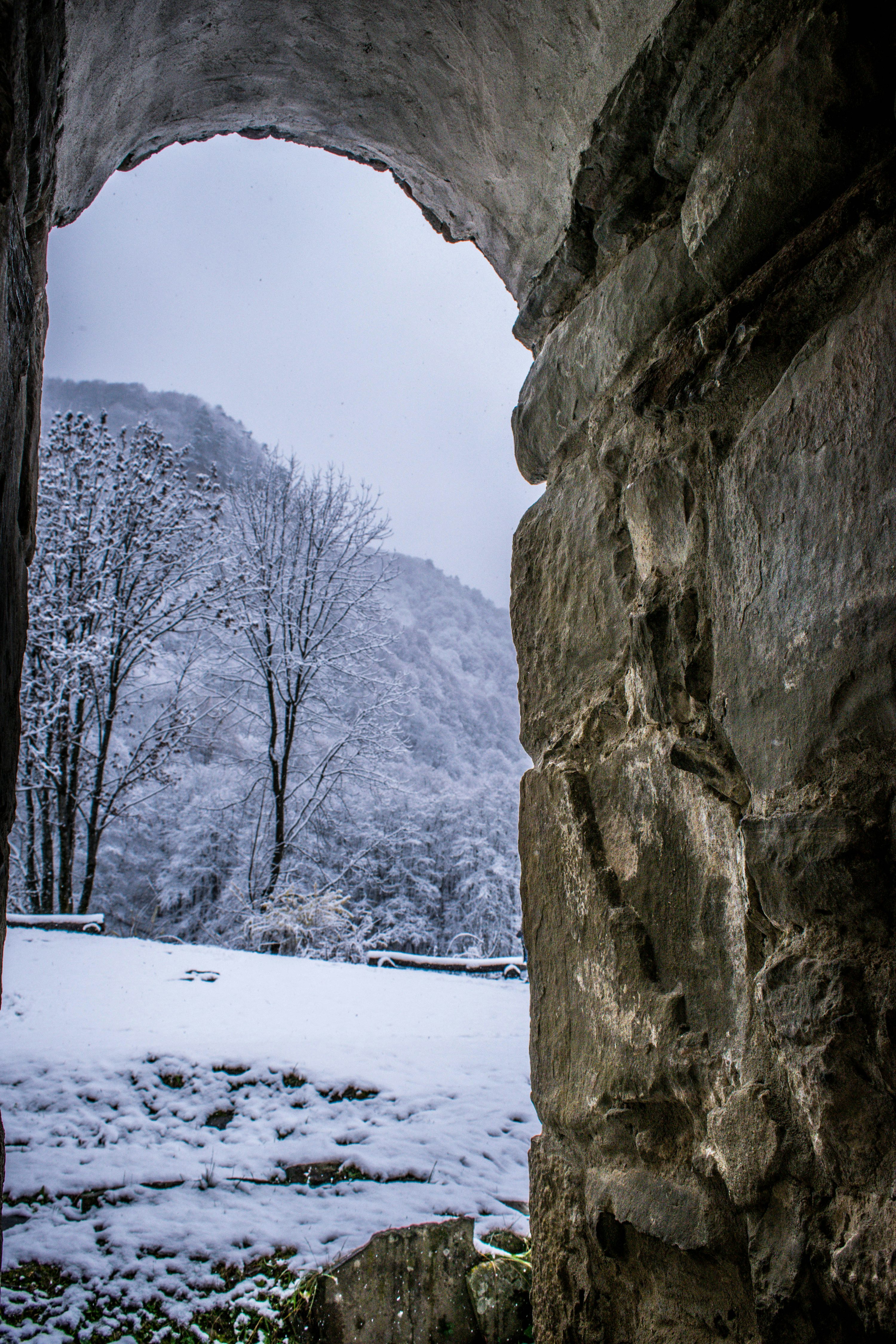 a view of a snowy mountain through a stone arch