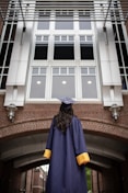 a person in a graduation gown standing in front of a building