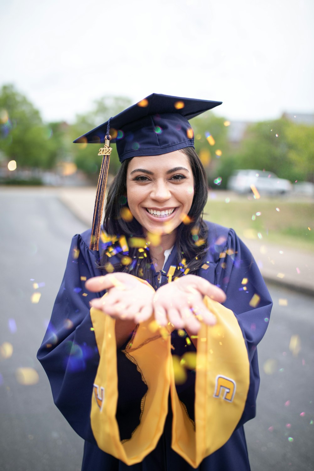 a woman in a graduation cap and gown throwing confetti
