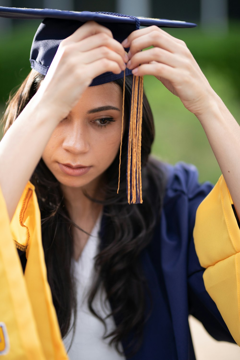 a woman in a cap and gown holds her graduation cap over her head