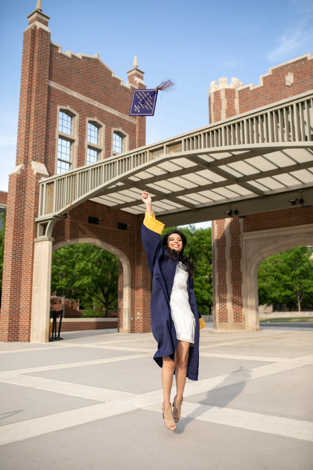 a woman in a white dress is holding a blue and yellow kite