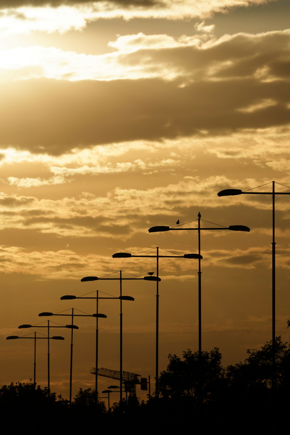 a row of street lights in front of a cloudy sky