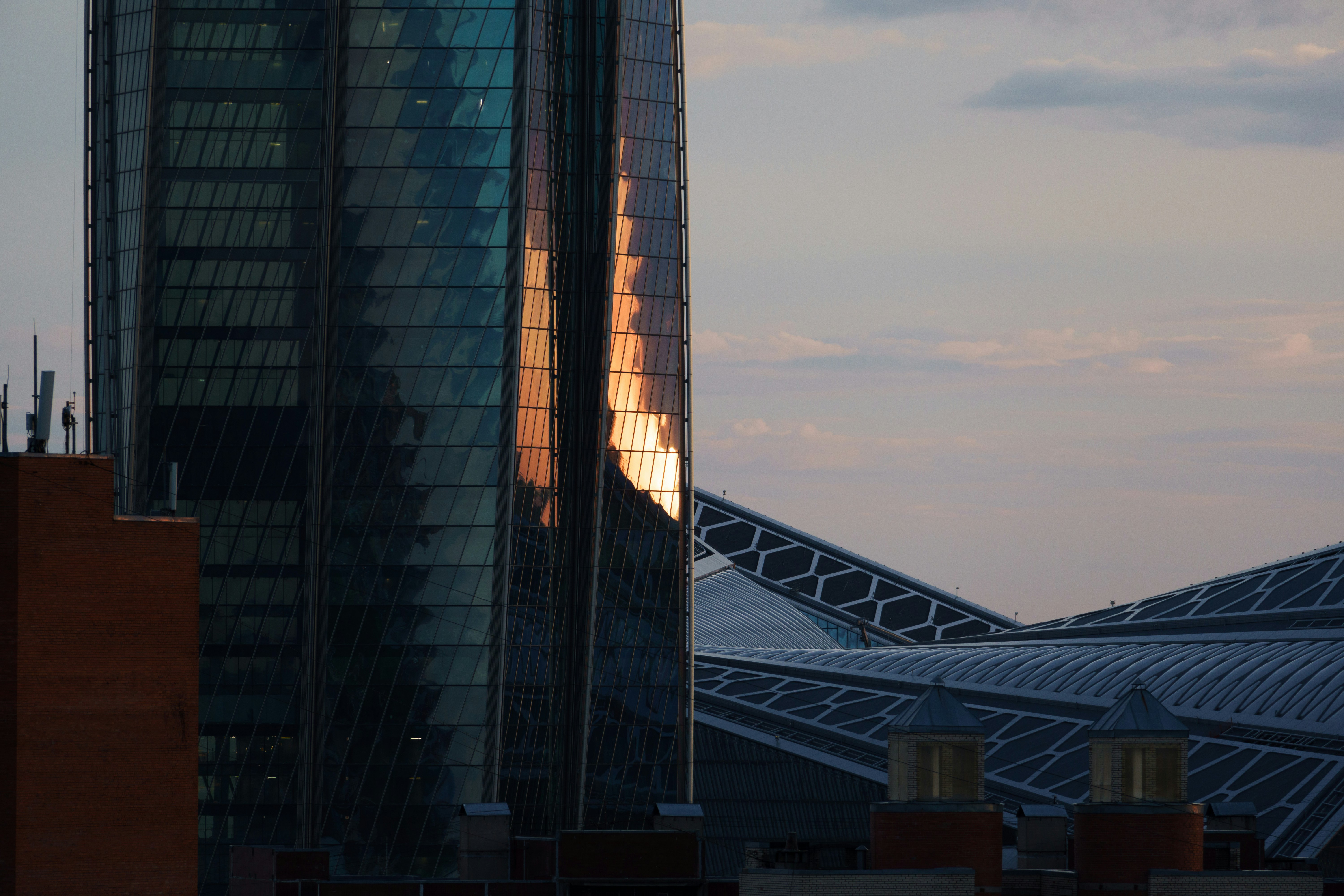 Modern glass office tower reflecting golden sunset light, airy sky, bright architectural photography