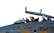 Two pilots wearing helmets are seated in the cockpit of a military aircraft. The cockpit canopy is open, and the aircraft has various markings, including the acronym 'IRIAF' on its body. The pilots are focused, suggesting a pre-flight preparation or taxiing scenario.