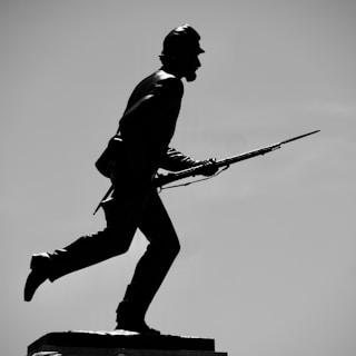 A shadowed silhouette of a vintage military uniform with a subtle, suggestive focus on the curve of a soldier's back.