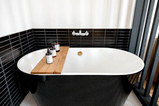 a bathtub with a wooden tray in a black and white bathroom