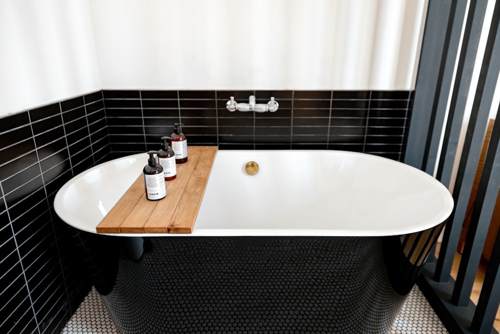 a bathtub with a wooden tray in a black and white bathroom
