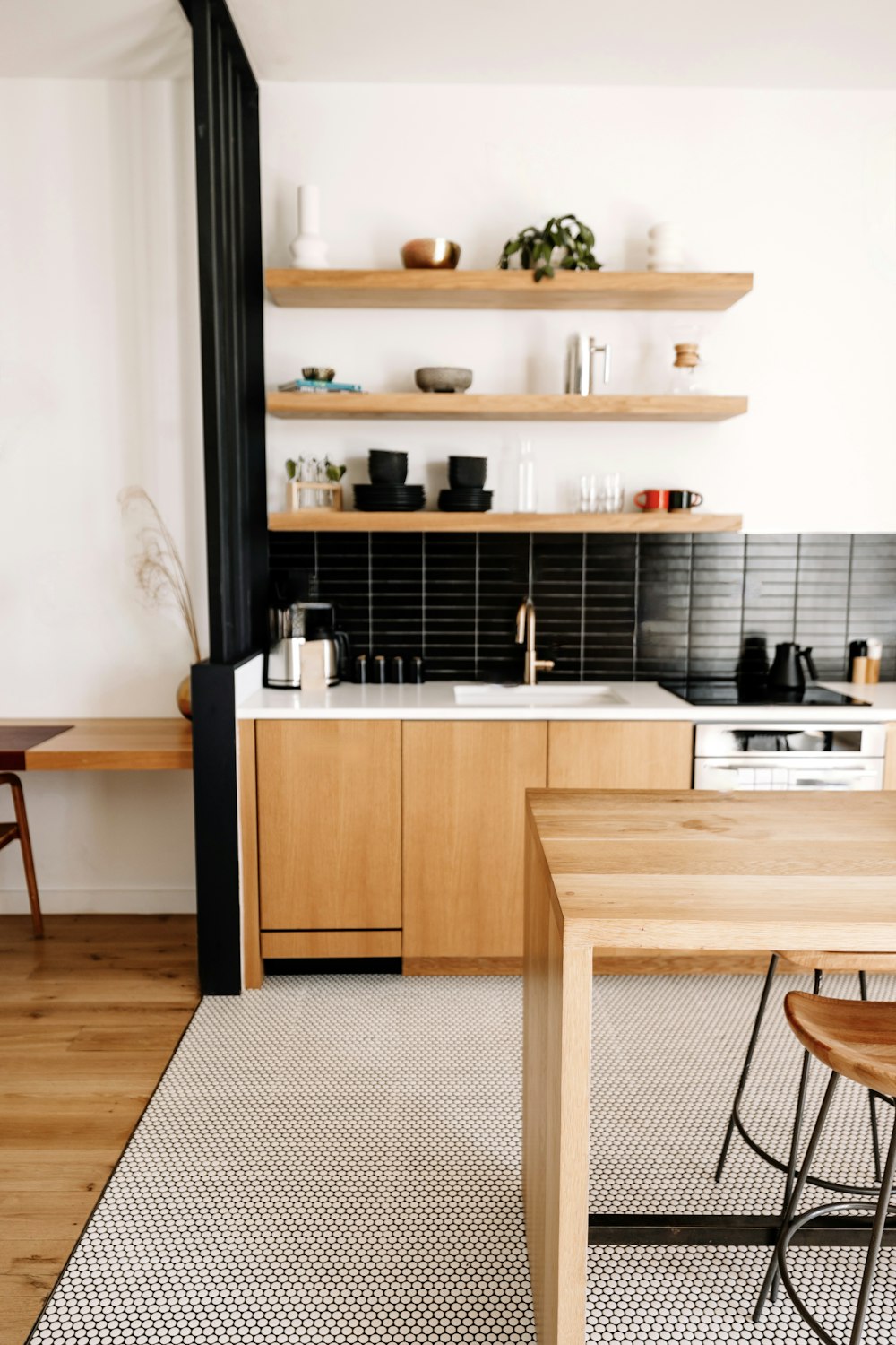 a kitchen with a wooden table and black tile backsplash