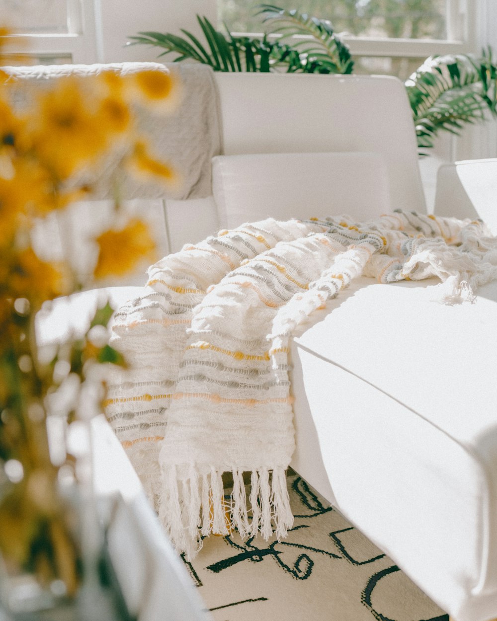a living room with a white couch and yellow flowers