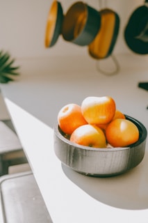 Warm kitchen scene showing a wooden bowl of fresh fruit on a natural wood table