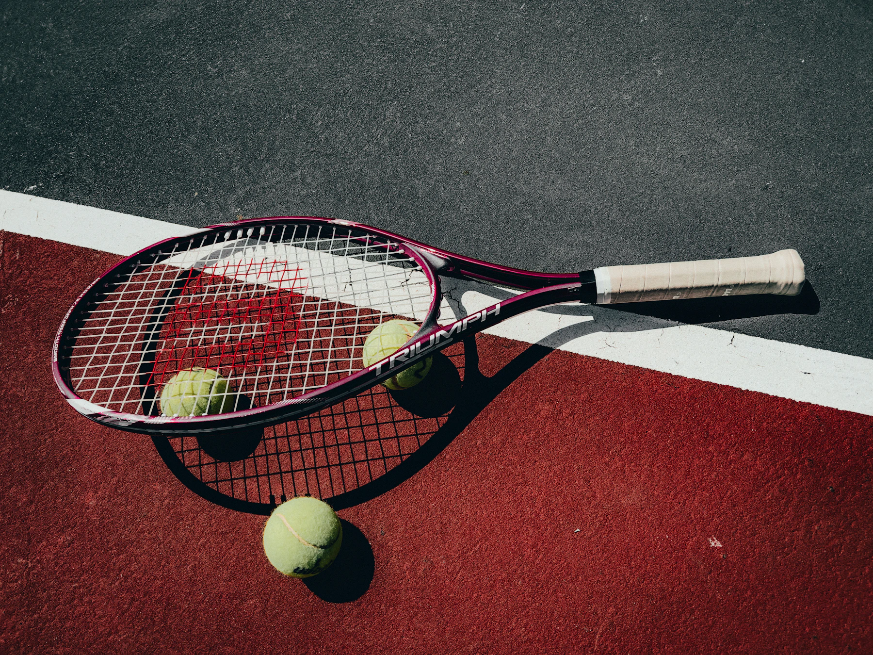 Raquette et balles posées sur un court de tennis extérieur