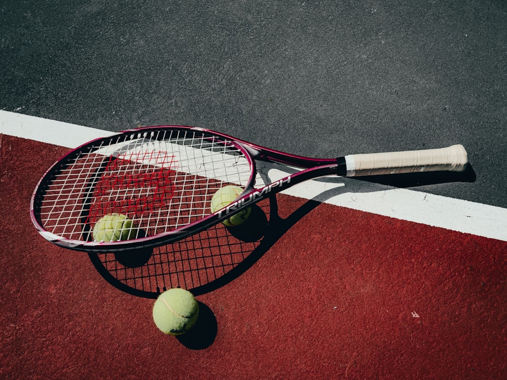 a tennis racket and three tennis balls on a tennis court