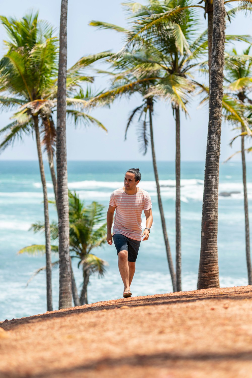 a man running on the beach with palm trees in the background