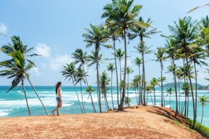 a woman standing on top of a sandy beach next to palm trees