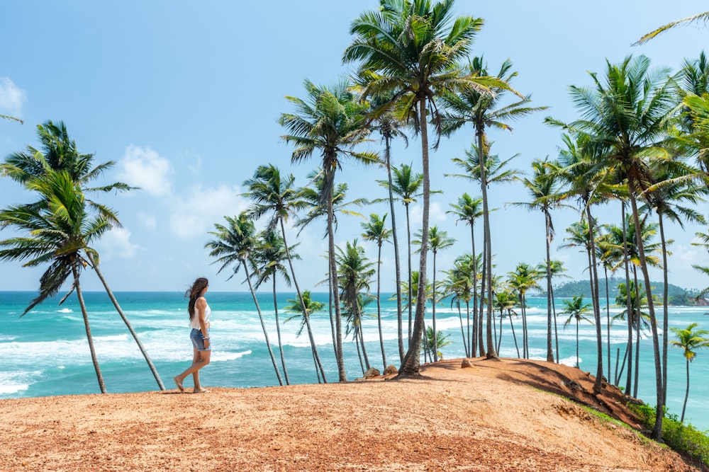 a woman standing on top of a sandy beach next to palm trees