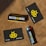 Several items are arranged on a brown textured surface, including a black and yellow gift card, a lighter with branding, and a box labeled 'Buzzed Buds'. The logo features a stylized bee symbol.