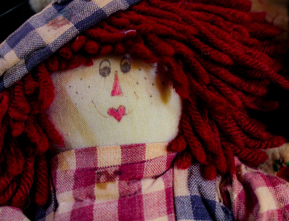 a cloth doll with red hair and a plaid shirt