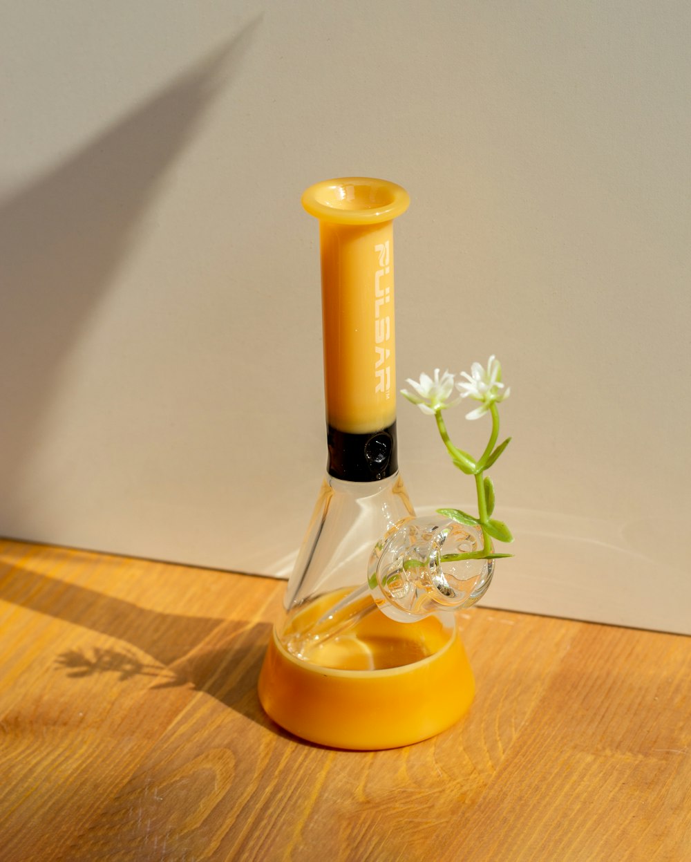 a yellow vase with a flower inside of it