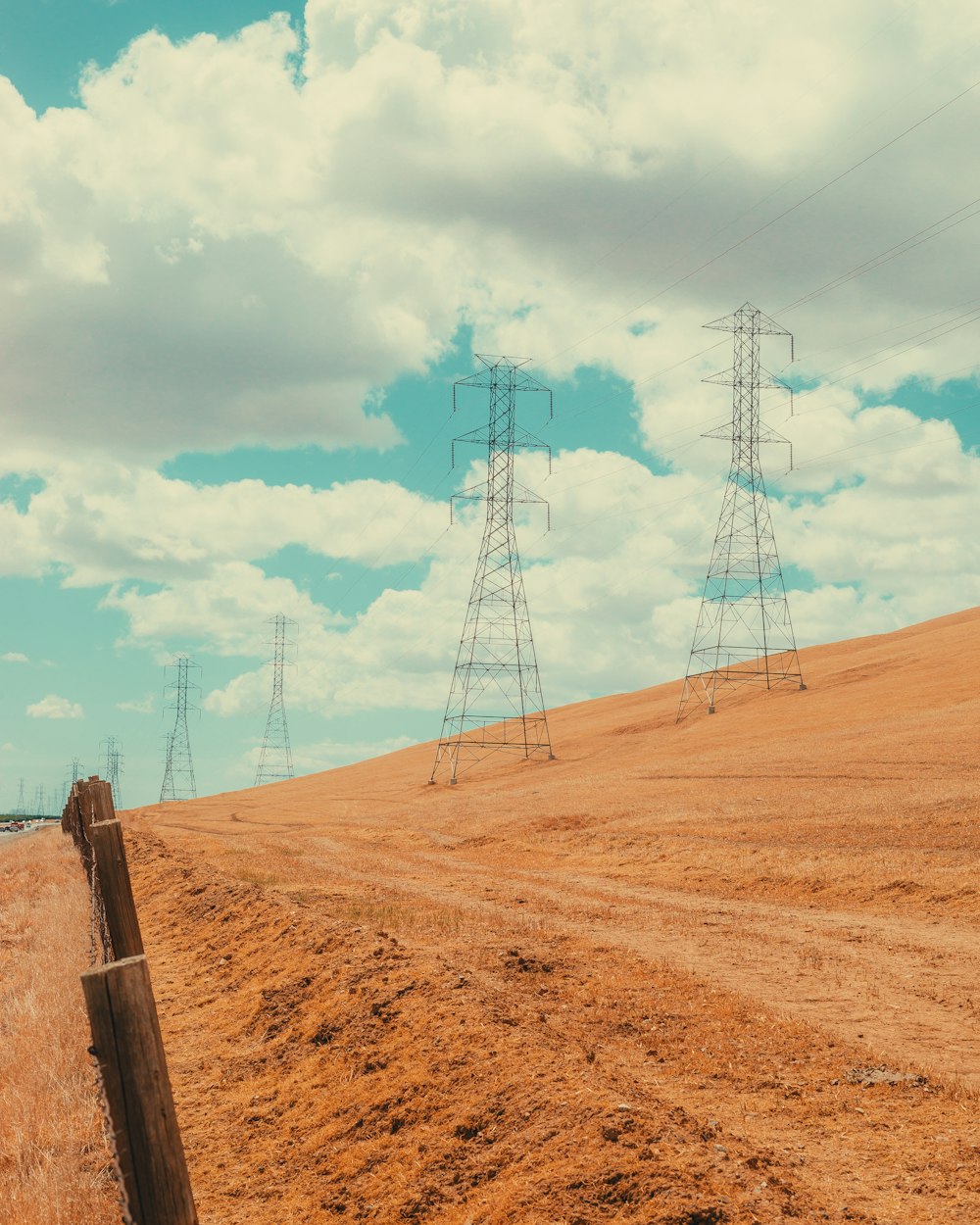 a dirt road with power lines in the distance