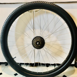 A sleek, modern bicycle wheel leaning against a wooden wall with soft natural light.