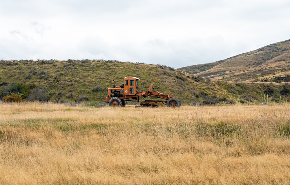 an old tractor in a field with a mountain in the background