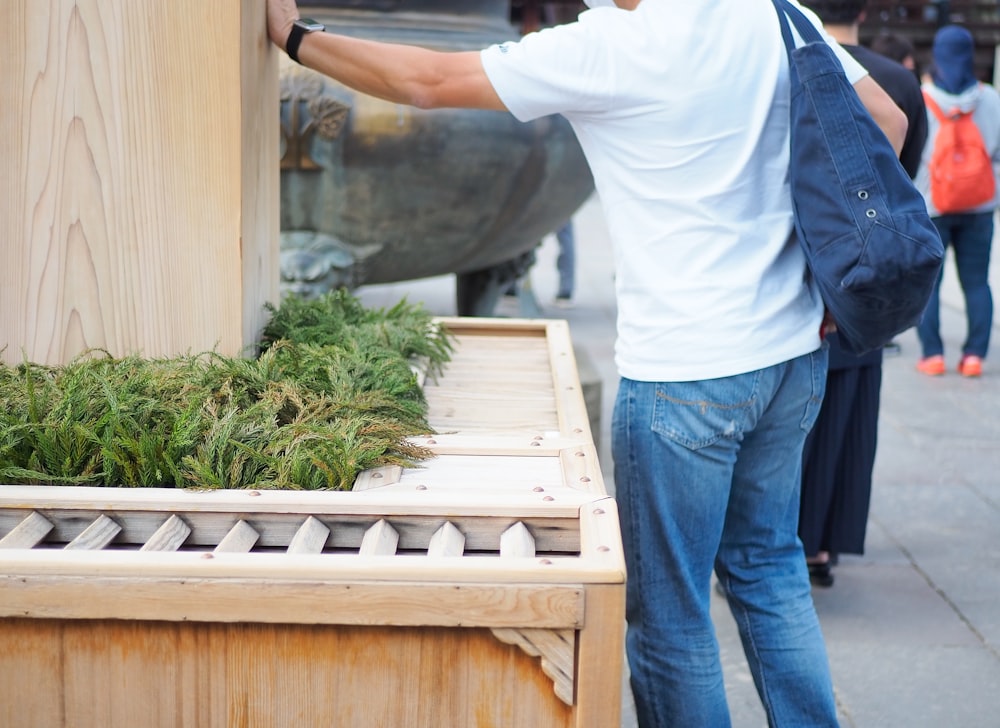 a man standing next to a wooden box filled with plants