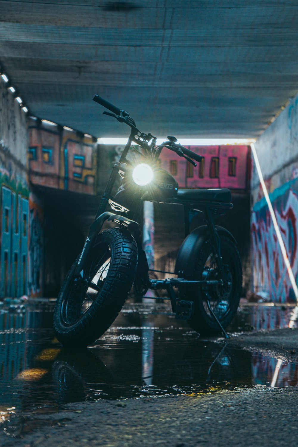 uma motocicleta estacionada em um túnel com pichações nas paredes