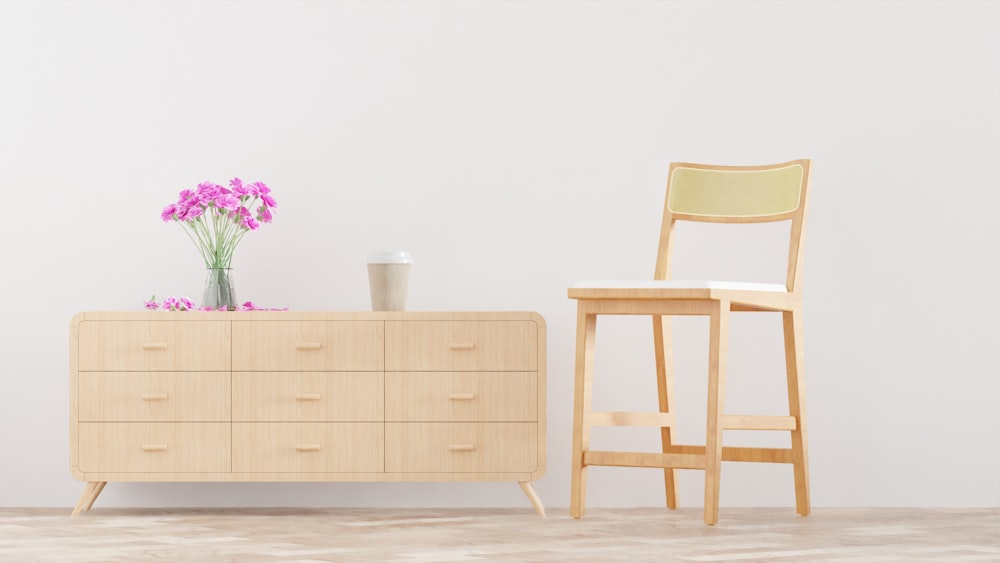 a chair and a dresser with a vase of flowers on it