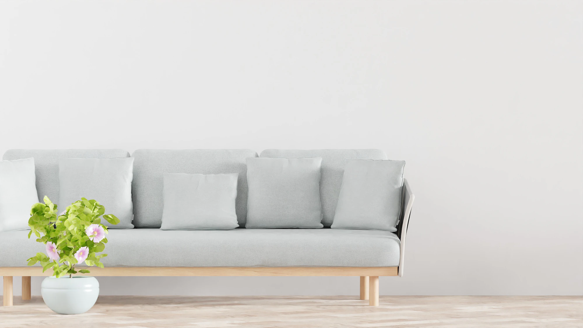 A living room with a light sofa against a large plain wall