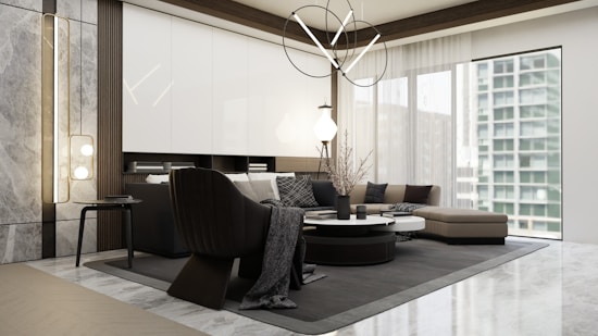 A modern living room with sleek, contemporary furniture including a black armchair and a sectional sofa in neutral tones. The room features a round coffee table with decorative items and large windows that allow natural light to illuminate the space. The walls are accented with a marble texture, and the ceiling has a unique, abstract chandelier.