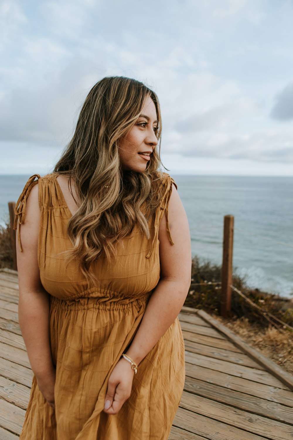 a woman in a brown dress standing on a boardwalk